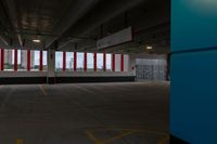 an empty parking garage with red and white striped windows over concrete floors and floor tiles