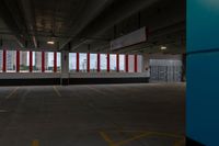 an empty parking garage with red and white striped windows over concrete floors and floor tiles