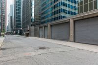 a group of commercial buildings in the city, with some parked cars behind them and some with closed metal doors