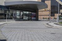 a person sitting at the bench in front of a mall that is empty of people