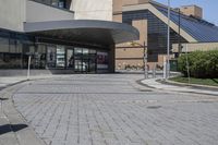 a person sitting at the bench in front of a mall that is empty of people