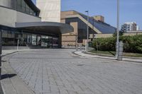 a person sitting at the bench in front of a mall that is empty of people