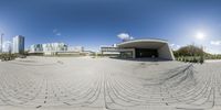 a 360 - lens photo shows people in the distance, and a building in the distance