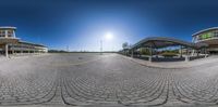 a 360 - view of a parking lot near buildings with blue skies and clouds in the background