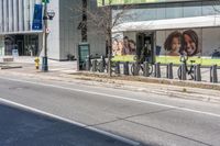 a city street has many bicycles chained to it and stores and businesses on the sides