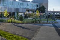 a city street surrounded by grass and tall buildings at the end of a street there is a paved pathway in front of the building