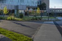 a city street surrounded by grass and tall buildings at the end of a street there is a paved pathway in front of the building