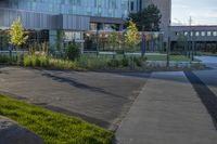 a city street surrounded by grass and tall buildings at the end of a street there is a paved pathway in front of the building