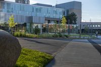 a city street surrounded by grass and tall buildings at the end of a street there is a paved pathway in front of the building