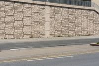 a city street that has a curb and some buildings next to it as well as the wall, as if it was from a car passing by