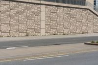 a city street that has a curb and some buildings next to it as well as the wall, as if it was from a car passing by