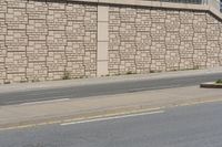 a city street that has a curb and some buildings next to it as well as the wall, as if it was from a car passing by