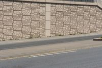 a city street that has a curb and some buildings next to it as well as the wall, as if it was from a car passing by