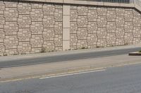 a city street that has a curb and some buildings next to it as well as the wall, as if it was from a car passing by