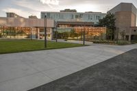 a city street surrounded by grass and tall buildings at the end of a street there is a paved pathway in front of the building