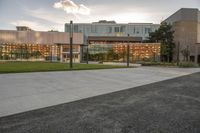 a city street surrounded by grass and tall buildings at the end of a street there is a paved pathway in front of the building