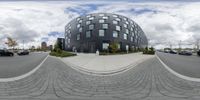 a fisheye lens shows cars parked on the side of the road near building with lots of windows