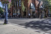 city street with traffic at an intersection and tall red brick building in the background with many windows