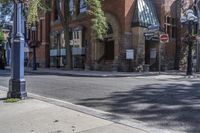 city street with traffic at an intersection and tall red brick building in the background with many windows