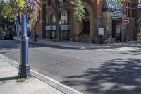 city street with traffic at an intersection and tall red brick building in the background with many windows