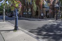 city street with traffic at an intersection and tall red brick building in the background with many windows