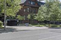 a person riding a bike in front of an old house on a city street by trees