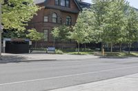 a person riding a bike in front of an old house on a city street by trees