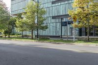 the woman is riding her bicycle through the city streets with some trees around her and an office building