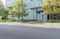 the woman is riding her bicycle through the city streets with some trees around her and an office building