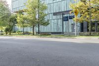 the woman is riding her bicycle through the city streets with some trees around her and an office building