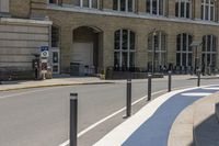 a woman walking down the sidewalk between two buildings next to the road with blue stripes on the sidewalk