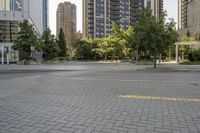 an empty, bricked road with lots of tall buildings and trees on the other side