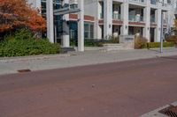 a red fire hydrant next to a white building on the sidewalk in the middle of an empty street