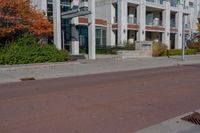 a red fire hydrant next to a white building on the sidewalk in the middle of an empty street