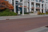 a red fire hydrant next to a white building on the sidewalk in the middle of an empty street