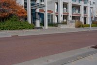 a red fire hydrant next to a white building on the sidewalk in the middle of an empty street