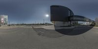 a 360 lens picture of the sun and building of an empty street with some people