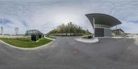 this is the view from a fish eye view of the corner of an oval, grey building on a street