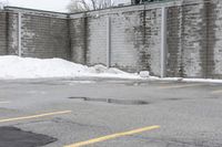 the empty parking lot has only snow on the ground in front of an old brick factory