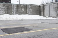 the empty parking lot has only snow on the ground in front of an old brick factory