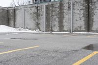 the empty parking lot has only snow on the ground in front of an old brick factory