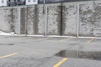 the empty parking lot has only snow on the ground in front of an old brick factory