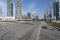 an empty city street with many skyscrapers and buildings near the end of the road