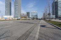 an empty city street with many skyscrapers and buildings near the end of the road