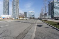 an empty city street with many skyscrapers and buildings near the end of the road