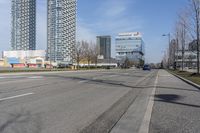 an empty city street with many skyscrapers and buildings near the end of the road