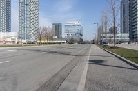 an empty city street with many skyscrapers and buildings near the end of the road