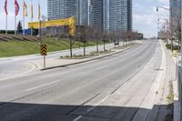 an empty street with cars driving down it and tall buildings in the background across the road