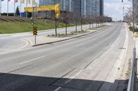 an empty street with cars driving down it and tall buildings in the background across the road