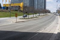 an empty street with cars driving down it and tall buildings in the background across the road